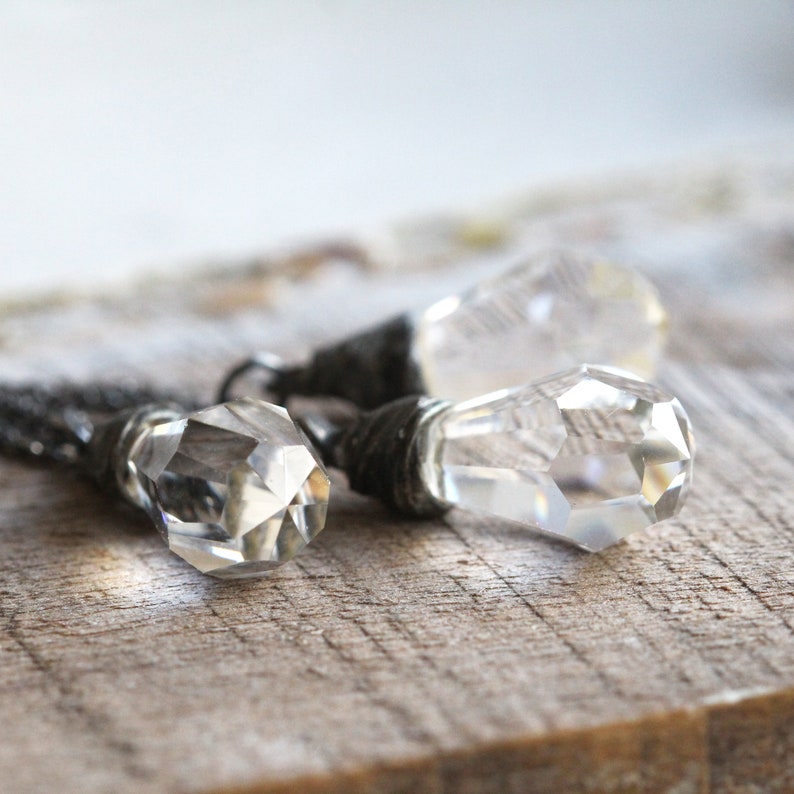 May include: Two crystal teardrop pendants with silver wire wrapped around the top of each pendant.