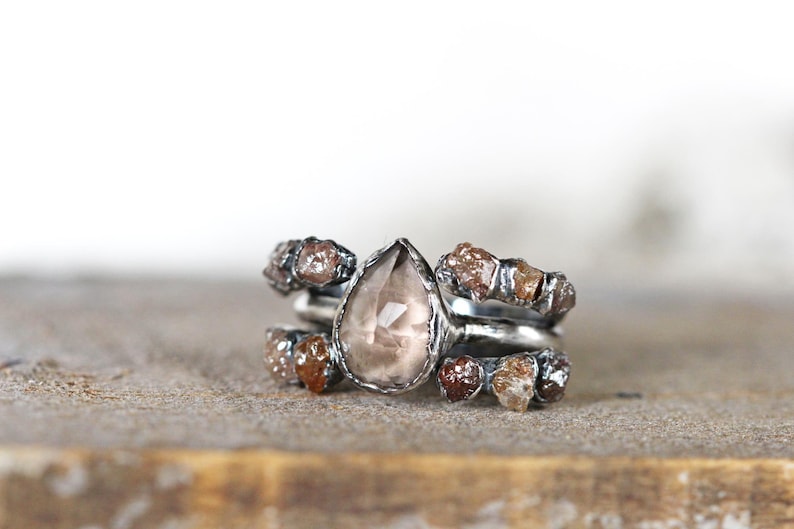 May include: A silver ring with a pear-shaped brown gemstone surrounded by smaller brown gemstones