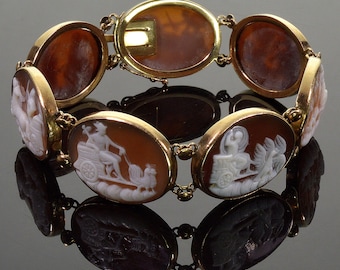 Puede incluir: Un brazalete de oro con un diseño de cadena de eslabones y engastes de camafeos ovalados. Los camafeos presentan figuras blancas sobre un fondo marrón.