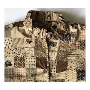 Peut inclure: Une chemise boutonnée en patchwork marron et beige avec un col à volants. La chemise présente un motif répétitif de cœurs, d'étoiles et de carreaux à carreaux. Le texte "Round and Round" est imprimé sur le tissu.
