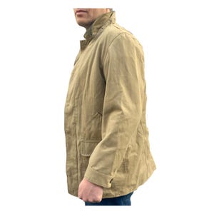 May include: A tan coloured jacket with a button up front and a flap pocket on the left side.