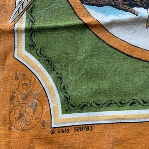 May include: Close-up of a vintage fabric with a nature-themed design. The fabric features a central green panel with a circular illustration of a bird and feather. The border is orange with decorative elements and the text "&copy; vista 829783".