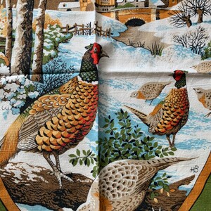 May include: A vintage fabric featuring a winter scene with pheasants. The fabric showcases a snowy landscape with houses, trees, and a bridge. The pheasants have brown, orange, and red plumage. The fabric is bordered with green and brown.