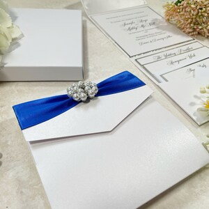 Magnifique échantillon de faire-part de mariage. Ruban bleu roi plissé et perles décoratives. Comprend une carte RSVP, des informations sur les clients et un menu.