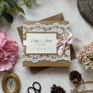 Échantillon d’invitation de mariage fait à la main. Dans un style rustique avec dentelle, ruban blush et perles. Comprend une carte RSVP, des informations sur les invités et un menu/poème cadeau