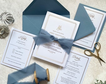 Folierte Hochzeitseinladungssuite mit ausgefranstem Chiffonband. Weißes und staubblaues Einladungsset mit Goldfolie.