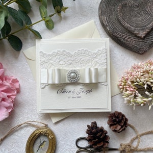 Handgemachte Hochzeitseinladung. Mit Vintage-Spitze, Plissee-Band und Perlenverzierung. Inklusive Antwortkarte, Gästeinfo und Menü.