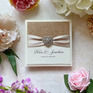 Glitzer Hochzeitseinladung Muster. Mit champagnerfarbenem Satinband & Herzverzierung. Inklusive RSVP Karte, Gästeinfo und Menü.