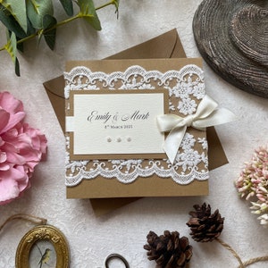 Échantillon d’invitation de mariage fait à la main. Dans un style rustique avec dentelle, ruban ivoire et perles. Comprend une carte RSVP, des informations sur les invités et un menu/poème cadeau