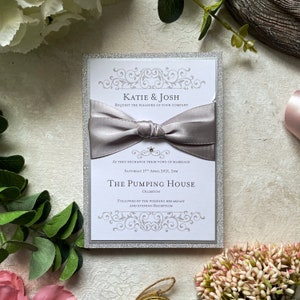 Échantillon d’invitation de mariage fait à la main. Invitation plate avec ruban et enveloppe. Argent et blanc 5x7 pouces. Carte pailletée et ruban de satin. Inc. RSVP