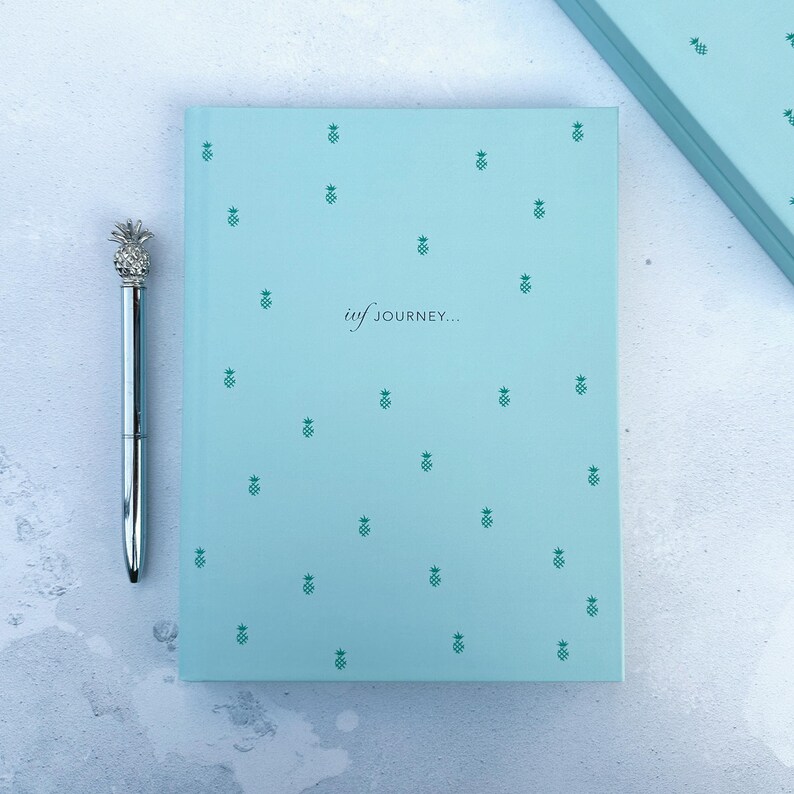 Flat lay image of the cover of the mint pineapple ivf planner, it details the new casebound cover and the text on the cover which says ivf journey.
