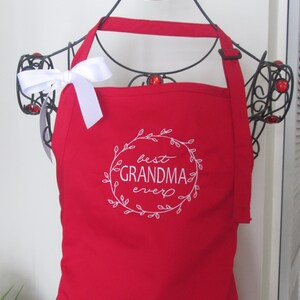 May include: Red apron with a white embroidered wreath that says "best grandma ever".