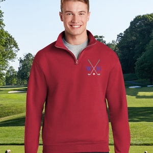 May include: A red quarter-zip sweatshirt with a golf club and ball design embroidered on the chest. The design includes the letters "W" and "H" in blue.