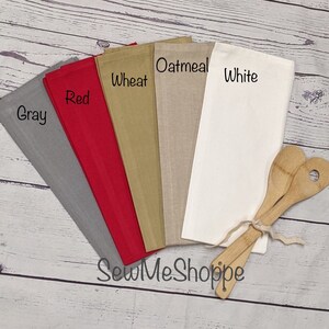 May include: Five kitchen towels in different colors: gray, red, wheat, oatmeal, and white. The towels are arranged in a fan shape with the gray towel at the bottom and the white towel at the top. The towels are all made of a soft, absorbent fabric. The text "SewMeShoppe" is printed on the bottom of the image.