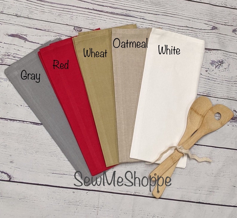 May include: Five kitchen towels in different colors: gray, red, wheat, oatmeal, and white. The towels are arranged in a fan shape with the gray towel at the bottom and the white towel at the top. The towels are all made of a soft, absorbent fabric. The text "SewMeShoppe" is printed on the bottom of the image.
