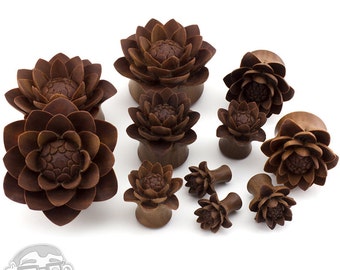 May include: A set of brown wooden lotus flower ear gauges in various sizes. The gauges are made of wood and have a detailed lotus flower design.