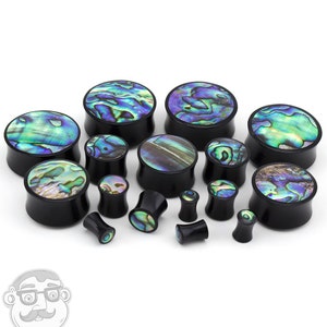 May include: A set of black and abalone shell ear gauges in various sizes. The gauges are made of wood and feature a unique abalone shell inlay.