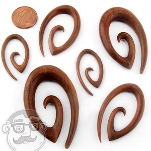 May include: Set of six wooden spiral ear gauges in various sizes. The gauges are brown and have a smooth, polished finish.