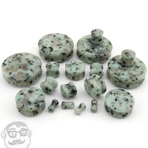 May include: A set of green and black speckled stone ear gauges in various sizes. The gauges are round and have a smooth, polished finish.