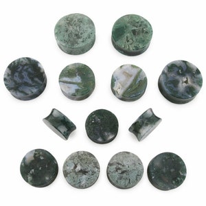 May include: A collection of moss agate stone ear plugs in various sizes and shapes. The plugs feature a mix of green, white, and gray patterns. Some are round, while others have a flared design. The natural stone plugs are displayed on a white background.