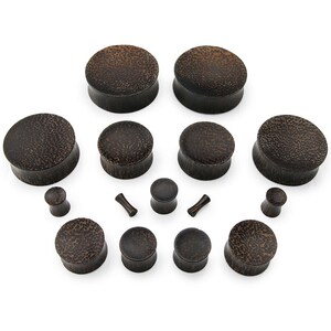 May include: A set of 12 wooden ear gauges in various sizes. The gauges are made of dark brown wood with a textured surface.
