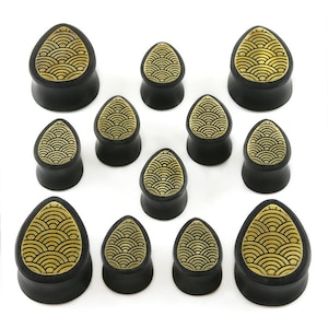 May include: Set of 12 black wood ear gauges with a gold wave pattern. The gauges are in various sizes.