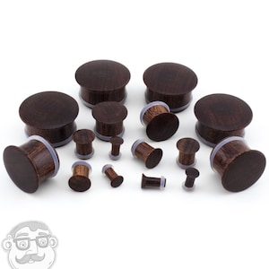 May include: A set of brown wooden ear gauges of various sizes. The gauges are made of wood and have a smooth, polished finish.