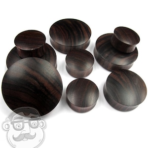 May include: A set of eight brown wood ear gauges in various sizes. The gauges are made of dark wood with a striped pattern.