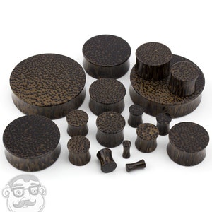May include: A set of brown wood ear gauges in various sizes. The gauges have a speckled pattern and are made from natural wood.