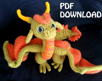 May include: A crocheted dragon toy in shades of green and orange. The dragon has large blue eyes, yellow horns, and orange wings. The text "PDF DOWNLOAD" is in white letters in the upper right corner.