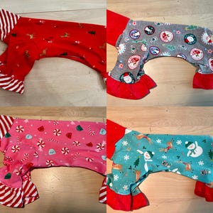 Peut inclure: Quatre pyjamas pour chien avec des imprimés sur le thème de Noël. Les pyjamas sont rouge, gris, rose et bleu sarcelle avec divers motifs de fêtes, notamment des cannes en sucre, des rennes, des bonhommes de neige et des sapins de Noël. Chaque pyjama a une bordure à volants rouge autour des manches et des jambes.