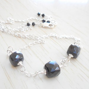 May include: A silver chain necklace with three black faceted gemstone beads.