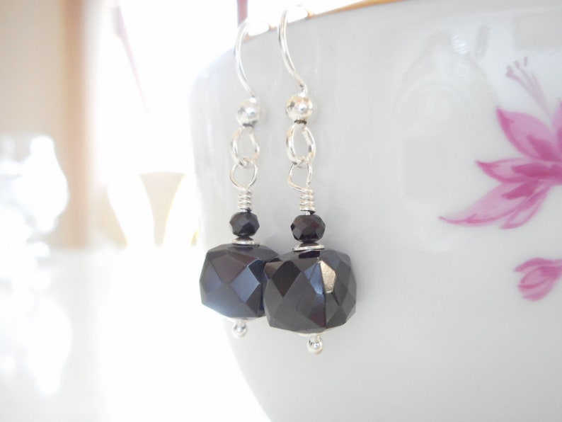May include: A pair of silver dangle earrings with black faceted gemstone drops.