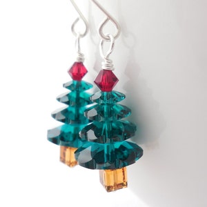 May include: Teal blue crystal Christmas tree earrings with a red crystal star on top and a gold crystal base.
