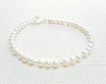 May include: A delicate white pearl bracelet with a silver clasp. The bracelet is made of small, round pearls and is perfect for adding a touch of elegance to any outfit.