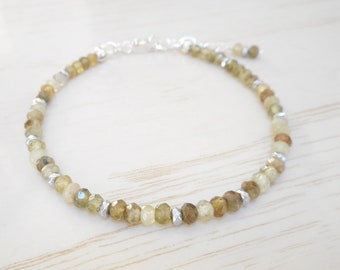 May include: A delicate bracelet made with small, faceted green and yellow gemstones and silver beads.