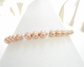 May include: A delicate bracelet made with a strand of blush-coloured pearls and silver accents.