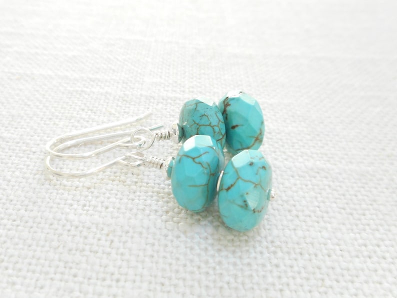 Puede incluir: Pendientes de piedra turquesa con ganchos de plata. Los pendientes tienen tres piedras turquesa, cada una con un patr&oacute;n &uacute;nico.