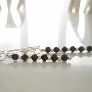 May include: A pair of silver earrings with black beads. The earrings are made with small silver beads and black faceted beads.
