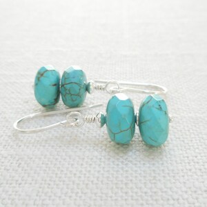 Puede incluir: Pendientes de piedras preciosas de color azul turquesa con ganchos de plata. Las piedras preciosas son facetadas y tienen un patr&oacute;n moteado.