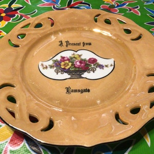Puede incluir: Un plato de cerámica decorativo de color marrón claro con un borde festoneado y un diseño recortado. El plato presenta un óvalo blanco con un diseño floral y el texto "A Present from Ramsgate".