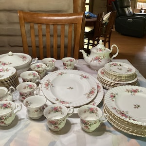 Könnte beinhalten: Ein Set weißes feines Porzellan-Geschirr mit einem Blumenmuster. Das Set enthält Teller, Schalen, Tassen, Untertassen, eine Teekanne und eine Servierplatte.