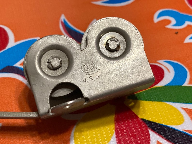 May include: A silver knife sharpener with two sharpening wheels and a handle. The sharpener has the text "ERGO U.S.A." printed on it.