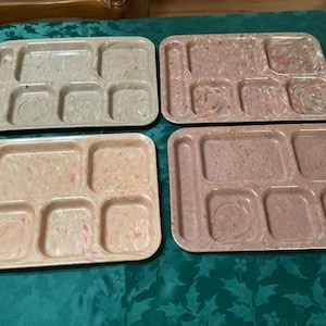 May include: Four rectangular cafeteria-style trays with six molded compartments each. The trays feature a speckled, marbled pattern in shades of beige, tan, pink, and mauve, with a smooth, glossy finish and rounded corners.