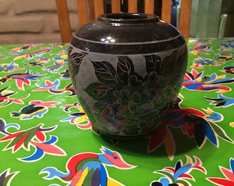 Può includere: Un vaso in ceramica nera con un motivo floreale. Il vaso ha una finitura liscia e lucida ed è decorato con un motivo floreale in rilievo.