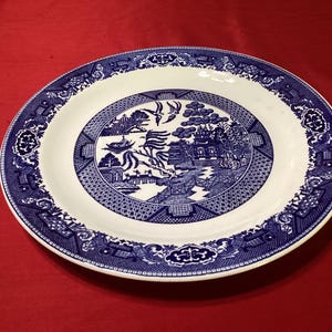 Puede incluir: Plato ovalado de cerámica blanca y azul con diseño Willow. El plato presenta una escena central con una pagoda, un puente y pájaros, rodeada por un borde azul con motivos florales y geométricos. Una pieza clásica para servir.