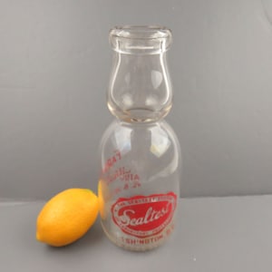 May include: A clear glass milk bottle with a red Sealtest label. The label has the words "The Sealtest Superior Dairy Products" and "Washington, D.C."