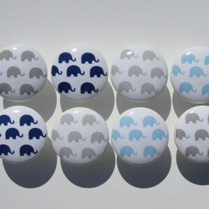 May include: Eight white ceramic knobs with a pattern of gray, blue, and light blue elephants.