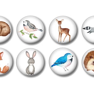 May include: Set of eight watercolor animal illustrations on white round buttons. The animals include a bear, a bird, a deer, a raccoon, a fox, a rabbit, a bluebird, and a hedgehog.