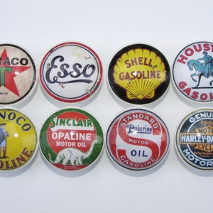May include: Eight vintage-style round ceramic knobs with various gas and motor oil company logos, including Texaco, Esso, Shell, Houston Gasoline, Conoco, Sinclair, Standard Oil, and Harley-Davidson.